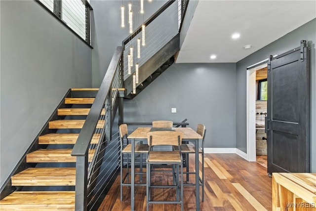 interior space featuring a barn door, wood finished floors, stairway, baseboards, and recessed lighting