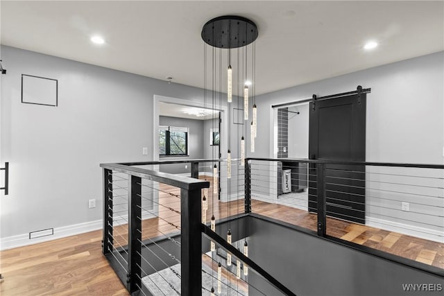 exercise room featuring baseboards, a barn door, light wood-style flooring, and recessed lighting