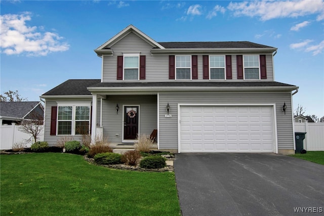 traditional-style home with fence, an attached garage, driveway, and a front lawn