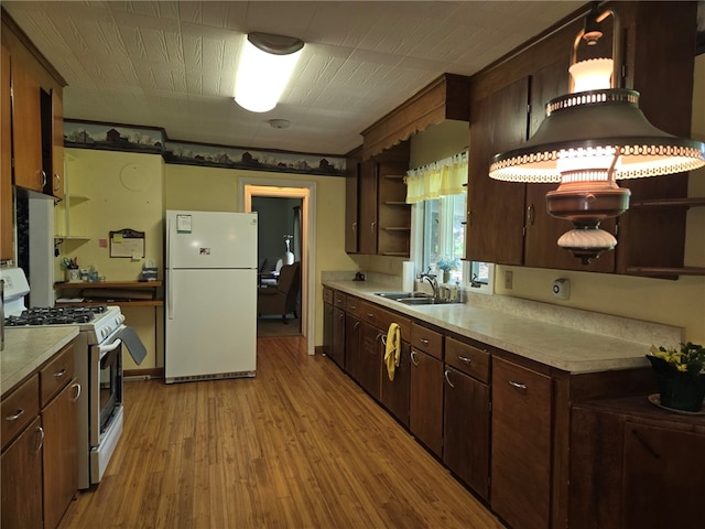 kitchen featuring open shelves, white appliances, light wood-style floors, light countertops, and a sink