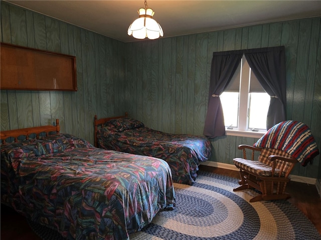 bedroom with wooden walls, baseboards, and wood finished floors