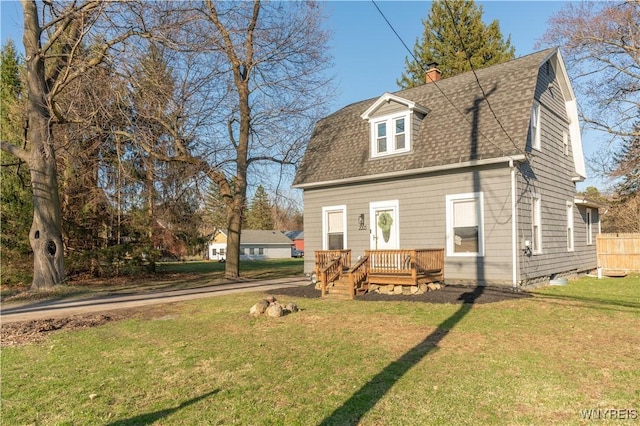view of front of property with roof with shingles, a wooden deck, a front yard, and a chimney
