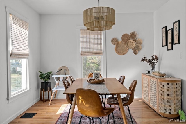 dining space with baseboards, light wood finished floors, and visible vents