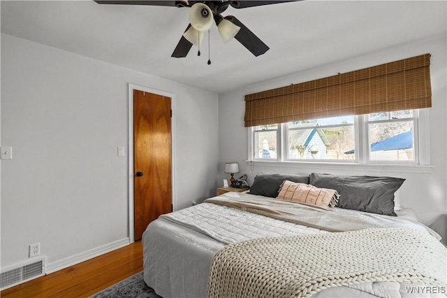 bedroom with visible vents, baseboards, ceiling fan, and wood finished floors