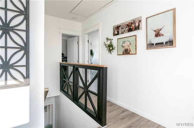 hallway with baseboards, attic access, and light wood-style flooring