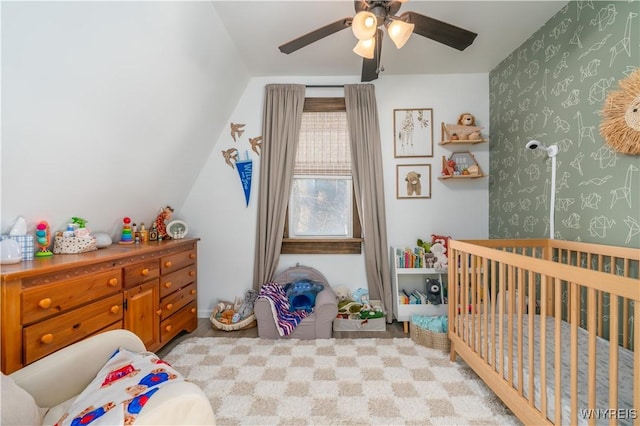 bedroom featuring a crib, ceiling fan, and lofted ceiling