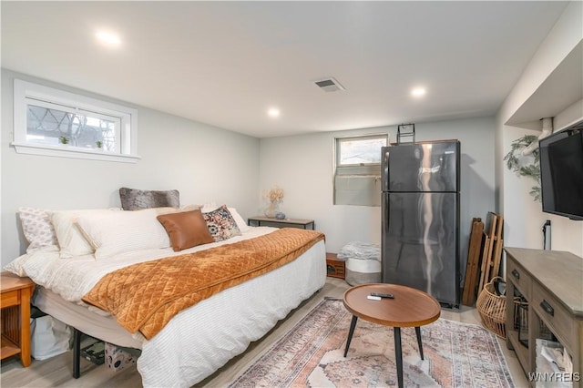 bedroom with visible vents, freestanding refrigerator, light wood-style floors, and recessed lighting