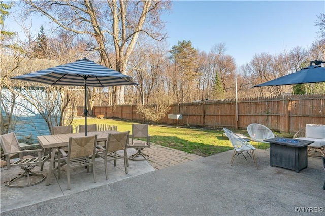 view of patio featuring a fenced backyard, outdoor dining space, and an outdoor fire pit