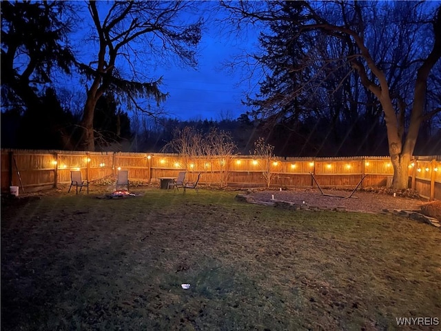 yard at twilight featuring a fenced backyard