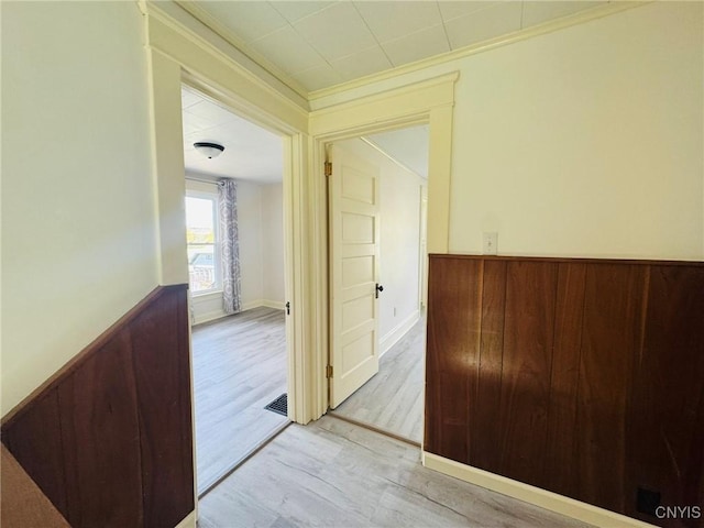 hallway featuring crown molding, wood finished floors, and a wainscoted wall