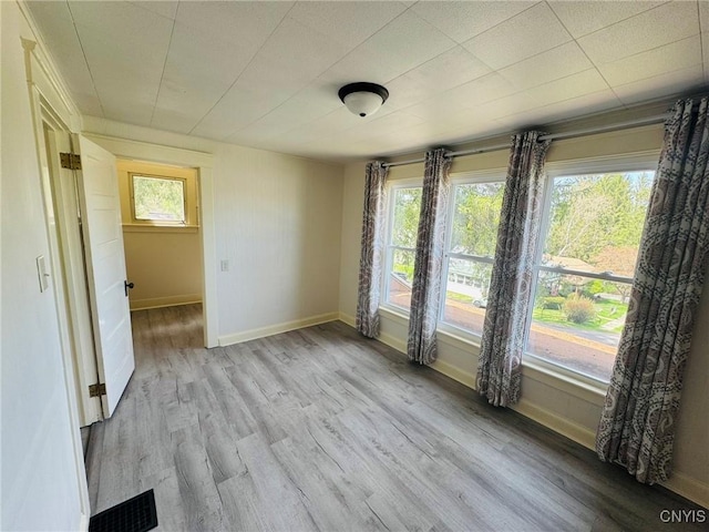 empty room featuring baseboards, light wood-style flooring, and visible vents