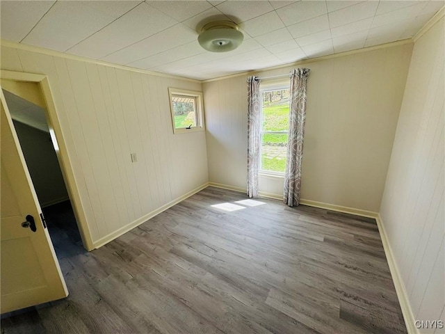 unfurnished room with baseboards, ornamental molding, and wood finished floors