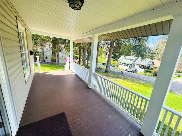 wooden deck with a porch, a yard, and a residential view