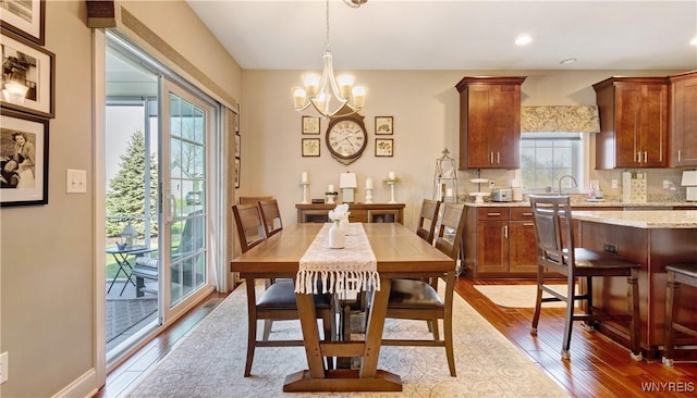 dining space featuring wood-type flooring, recessed lighting, and a notable chandelier