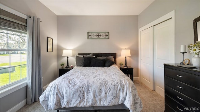 bedroom with light colored carpet, multiple windows, and a closet