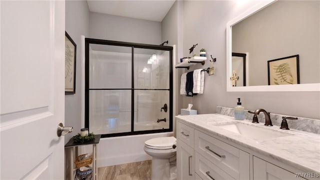 bathroom featuring vanity, bath / shower combo with glass door, and toilet