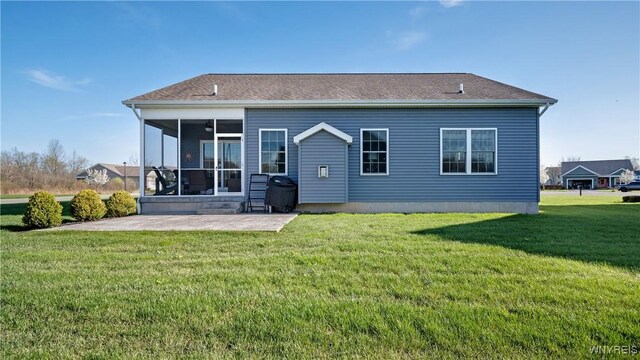 back of house with a lawn, a shingled roof, a patio area, and a sunroom