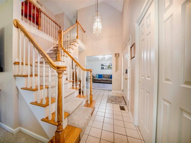 foyer featuring stairway, high vaulted ceiling, baseboards, and tile patterned floors