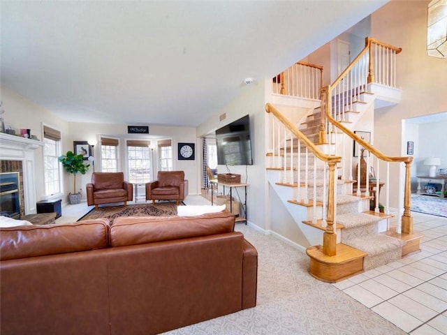 carpeted living area featuring baseboards, stairs, and a glass covered fireplace