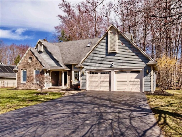 view of front of property featuring brick siding, a garage, driveway, and a front yard
