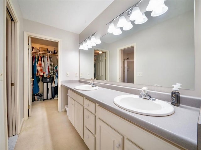 full bathroom featuring a sink, a walk in closet, a shower with shower door, and double vanity