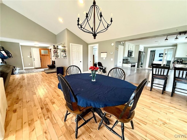 28053 Boat Launch Rd, Lyme, NY 13622 - dining area featuring light wood-type flooring, baseboards, a notable chandelier, and high vaulted ceiling