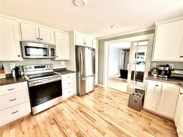28053 Boat Launch Rd, Lyme, NY 13622 - kitchen with dark countertops, appliances with stainless steel finishes, white cabinets, ornamental molding, and light wood-style flooring