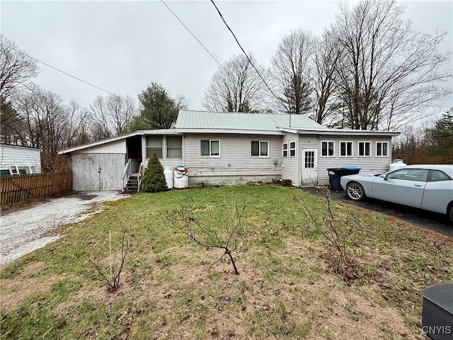 ranch-style house with fence, metal roof, and a front lawn