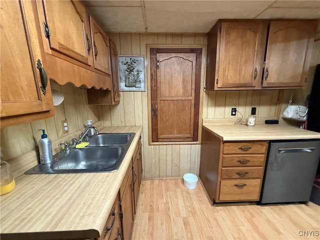 kitchen with light countertops, brown cabinetry, a sink, and light wood finished floors