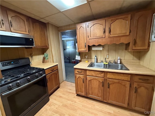 kitchen featuring light countertops, stainless steel microwave, a sink, and black range with gas stovetop