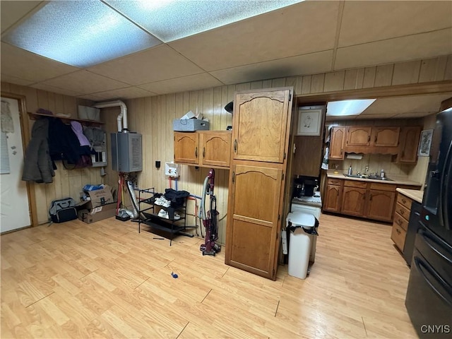 interior space with light countertops, wooden walls, water heater, and light wood-style floors