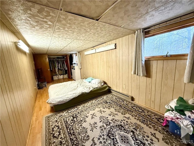 bedroom featuring a baseboard radiator, wood finished floors, and wooden walls