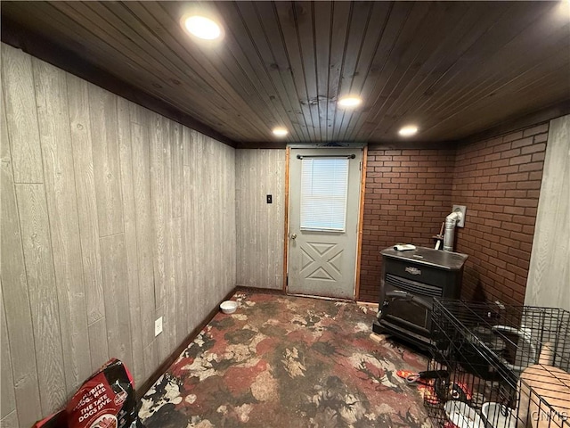 interior space with a wood stove, wooden walls, and wooden ceiling