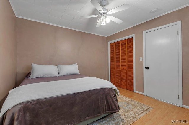 bedroom with crown molding, a ceiling fan, a closet, and light wood finished floors