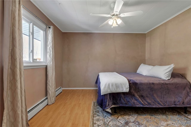 bedroom with ceiling fan, baseboards, wood finished floors, a baseboard heating unit, and ornamental molding