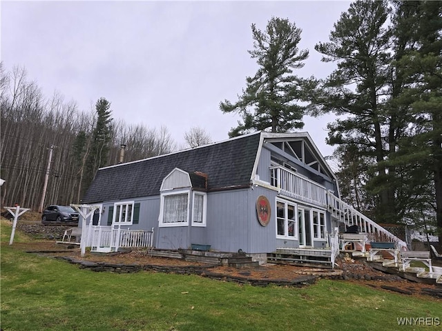 view of front of property with a gambrel roof, stairway, a front yard, and a shingled roof