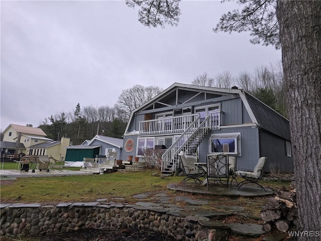 back of property featuring a gambrel roof, roof with shingles, a patio area, a yard, and stairway