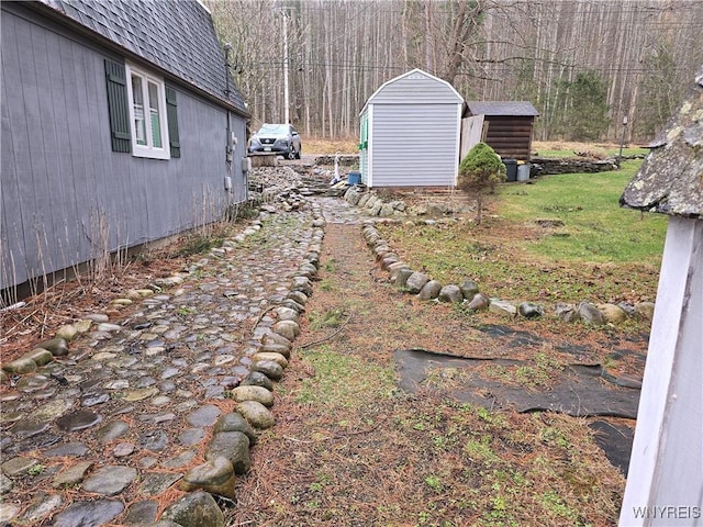 view of yard featuring a storage unit, an outdoor structure, and a view of trees