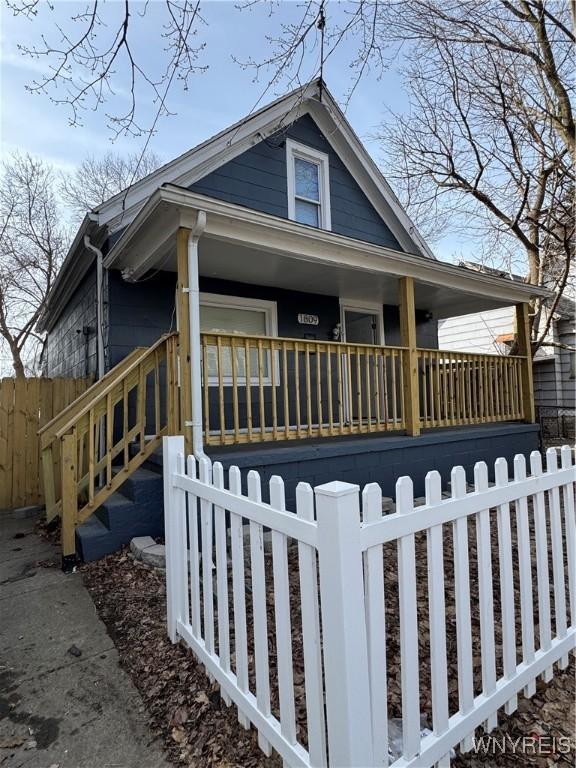 view of front of property featuring covered porch, a fenced front yard, and stairs