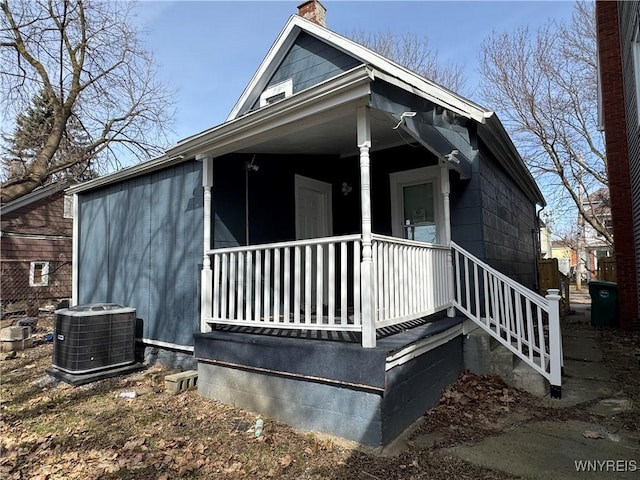view of front of property with covered porch, a chimney, and cooling unit