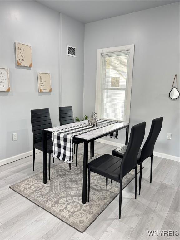dining space with light wood-type flooring, baseboards, and visible vents