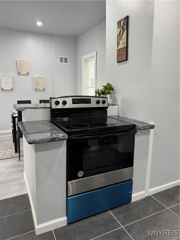 kitchen with stainless steel electric range oven, baseboards, tile patterned flooring, and visible vents