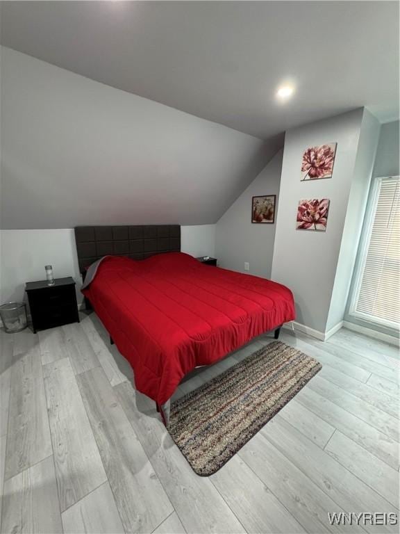 bedroom with baseboards, light wood-style flooring, and lofted ceiling