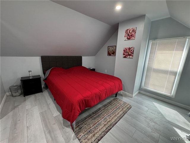 bedroom featuring baseboards, vaulted ceiling, and light wood-style flooring