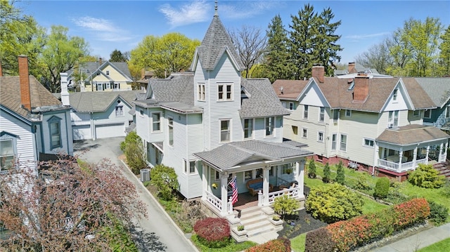 exterior space featuring a residential view, roof with shingles, a garage, cooling unit, and covered porch
