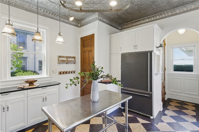 kitchen with arched walkways, hanging light fixtures, white cabinets, dark floors, and high end fridge