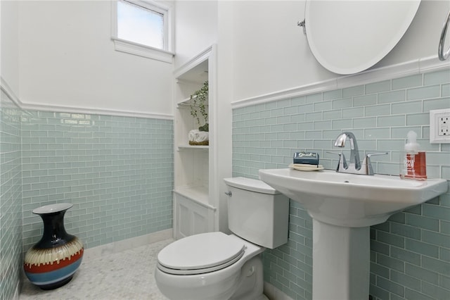 bathroom featuring toilet, tile walls, and wainscoting