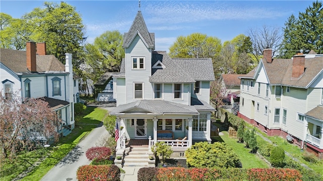 victorian home with roof with shingles, covered porch, and a residential view