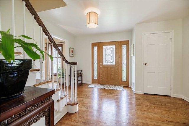entryway with baseboards, stairway, and light wood-style floors