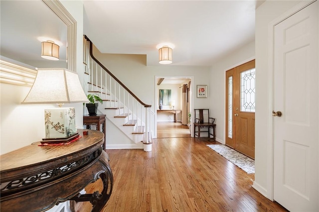 entryway with stairway, baseboards, and wood finished floors